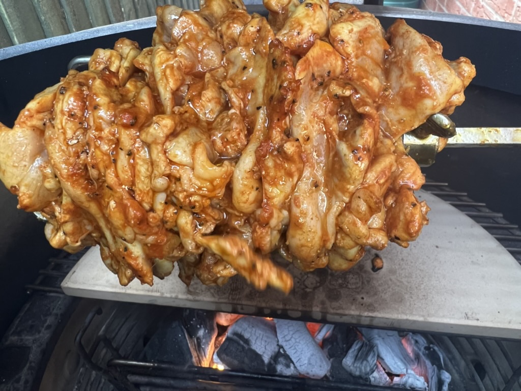 Marinated chicken shawarma stacked tightly on a rotisserie spit before browning fully