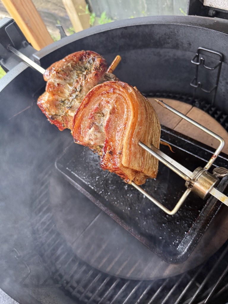 Porchetta cooking on a Joetisserie spit inside a Kamado Joe
